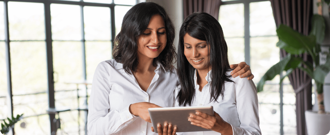 two-smiling-female-colleagues-using-tablet-pc-cafe